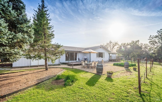 rear view of property featuring a patio, a lawn, and fence