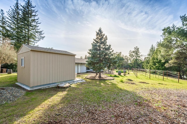 view of yard featuring fence, an outbuilding, and a shed