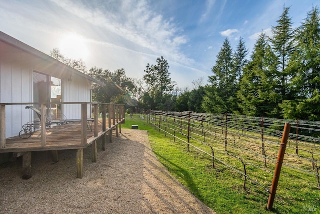 view of yard with a rural view, a deck, and fence