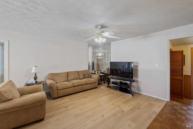 living room featuring a wainscoted wall, a textured ceiling, a ceiling fan, and wood finished floors