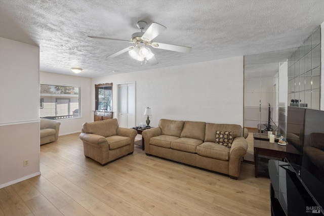 living area with a textured ceiling, baseboards, light wood finished floors, and ceiling fan