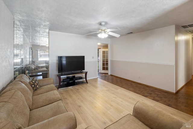 living room with visible vents, baseboards, parquet floors, and a ceiling fan