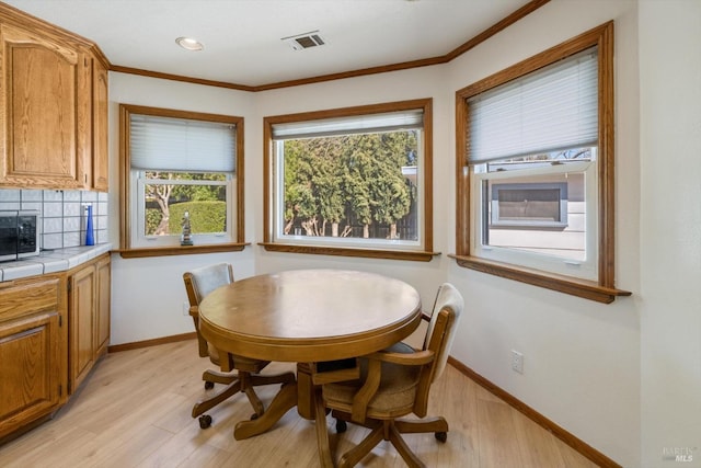 dining space with visible vents, baseboards, crown molding, and light wood-style floors