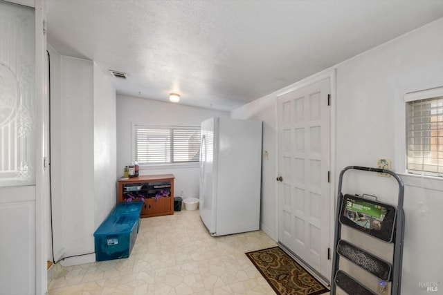 washroom with visible vents, heating unit, and a textured ceiling