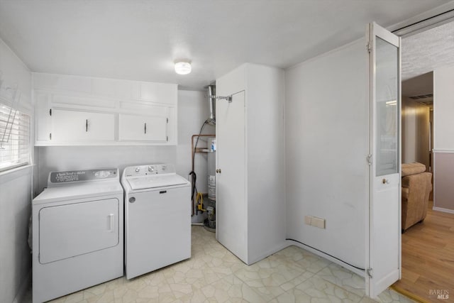 laundry room with strapped water heater, cabinet space, and washing machine and clothes dryer