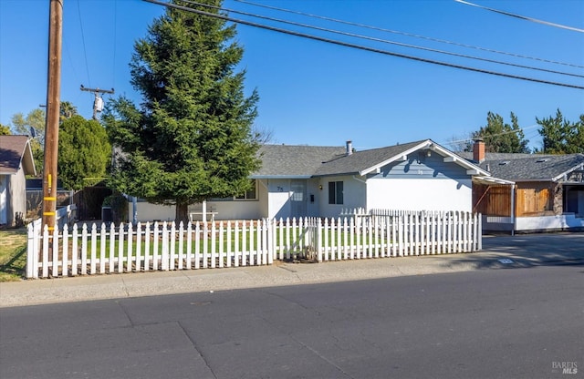 ranch-style house featuring a fenced front yard and roof with shingles
