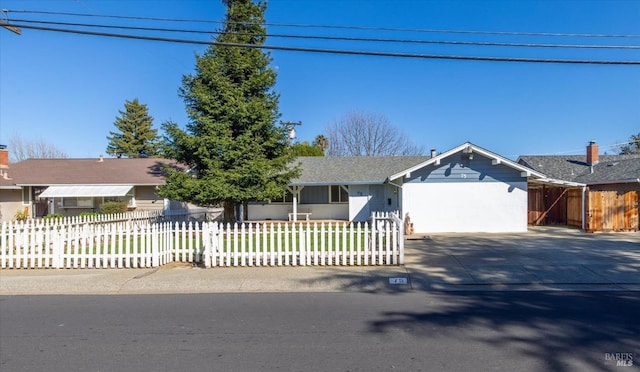 ranch-style home featuring a fenced front yard, an attached garage, and concrete driveway