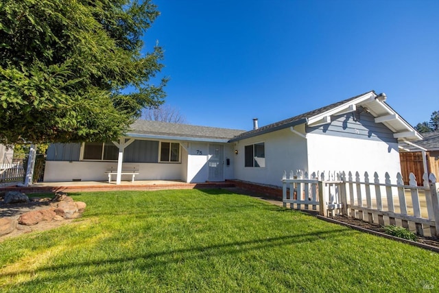 rear view of house with stucco siding, a lawn, and fence