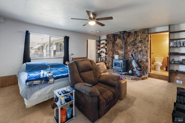 carpeted living area with ceiling fan, a wood stove, visible vents, and a textured ceiling