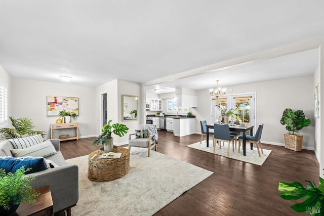 living area featuring a healthy amount of sunlight, baseboards, an inviting chandelier, and dark wood-style flooring