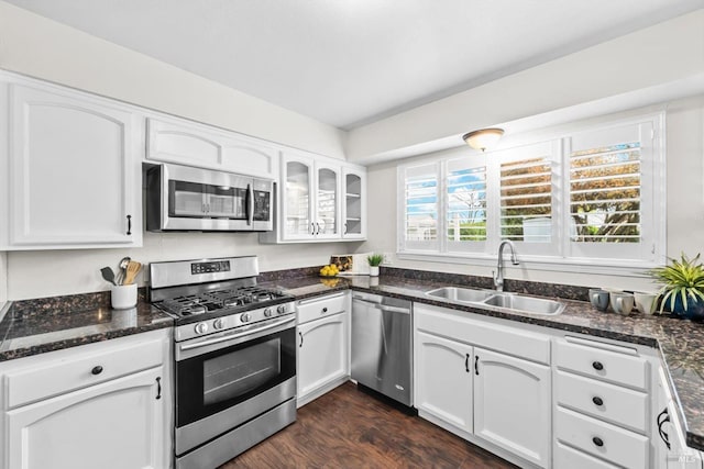 kitchen featuring dark stone countertops, white cabinetry, stainless steel appliances, and a sink