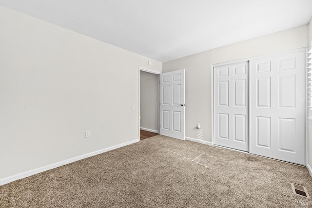 unfurnished bedroom featuring carpet, visible vents, a closet, and baseboards