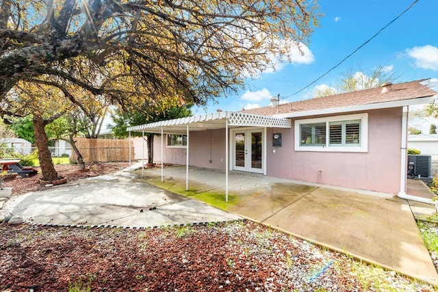 back of house with fence, central AC unit, stucco siding, french doors, and a patio