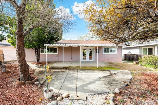 rear view of house with french doors, a patio area, stucco siding, and fence