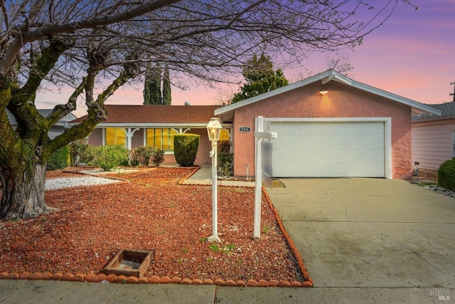 ranch-style home featuring an attached garage, driveway, and stucco siding