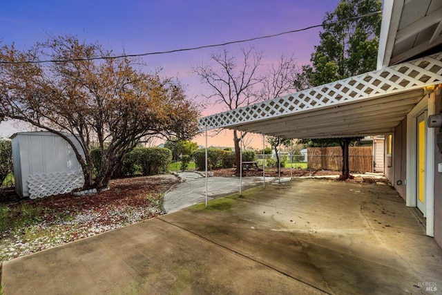 view of patio / terrace with a storage unit, a carport, an outdoor structure, and fence