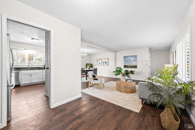 living room with baseboards, a notable chandelier, and dark wood finished floors