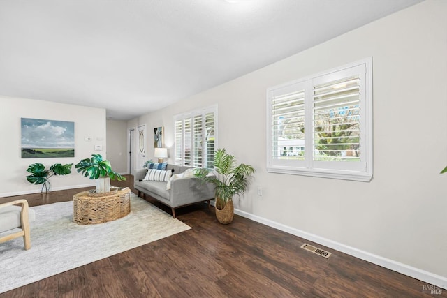 living area featuring dark wood finished floors, plenty of natural light, baseboards, and visible vents