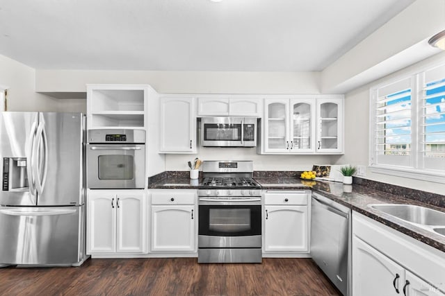 kitchen featuring glass insert cabinets, dark wood finished floors, white cabinets, stainless steel appliances, and open shelves