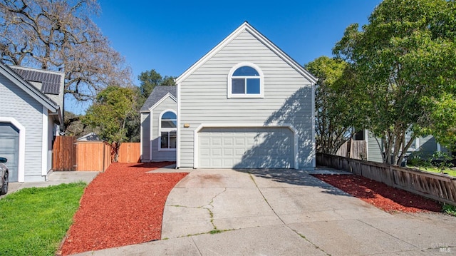 traditional-style home featuring an attached garage, concrete driveway, and fence