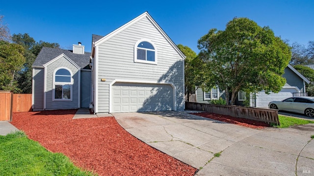 traditional-style home featuring an attached garage, concrete driveway, and fence