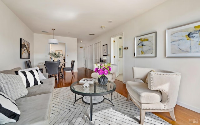 living room featuring wood finished floors, visible vents, and baseboards