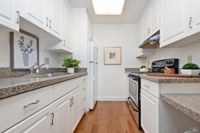 kitchen featuring under cabinet range hood, freestanding refrigerator, stainless steel range with electric cooktop, light wood-style floors, and white cabinets