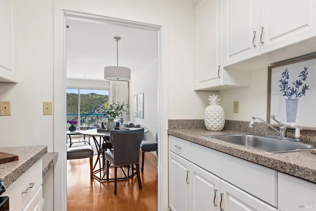 kitchen with a sink, light wood-style flooring, and white cabinetry