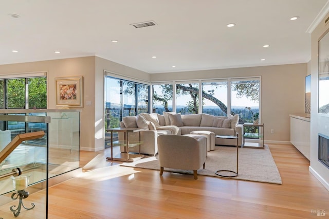 living room featuring baseboards, visible vents, recessed lighting, a glass covered fireplace, and light wood-type flooring