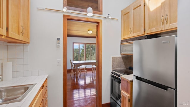 kitchen featuring light brown cabinetry, range with electric cooktop, tasteful backsplash, freestanding refrigerator, and tile countertops