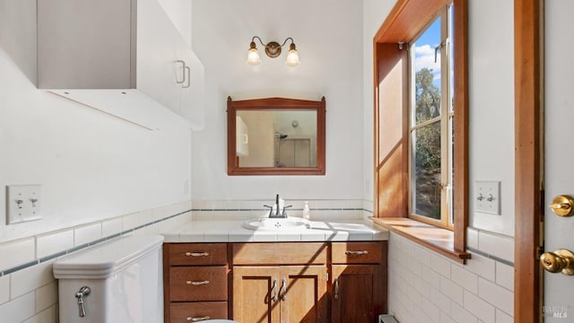 bathroom with vanity, a wainscoted wall, and tile walls