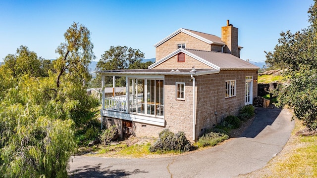 view of side of property featuring a chimney, crawl space, stone siding, and metal roof