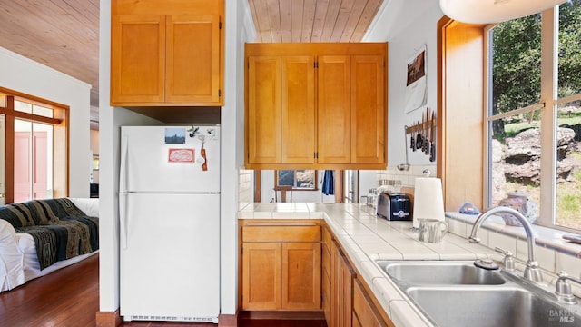 kitchen featuring tile counters, a sink, wood ceiling, dark wood-style floors, and freestanding refrigerator