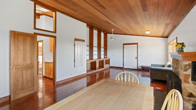 dining space featuring baseboards, a ceiling fan, wood finished floors, wooden ceiling, and a fireplace