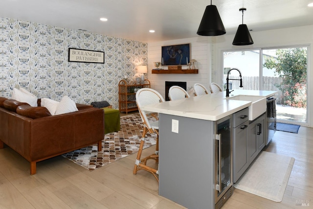 kitchen with a sink, a large fireplace, gray cabinetry, and open floor plan