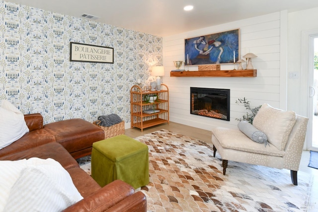 living room with a glass covered fireplace, recessed lighting, and visible vents