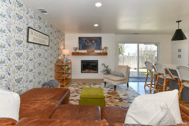 living room featuring a glass covered fireplace, recessed lighting, visible vents, and wallpapered walls