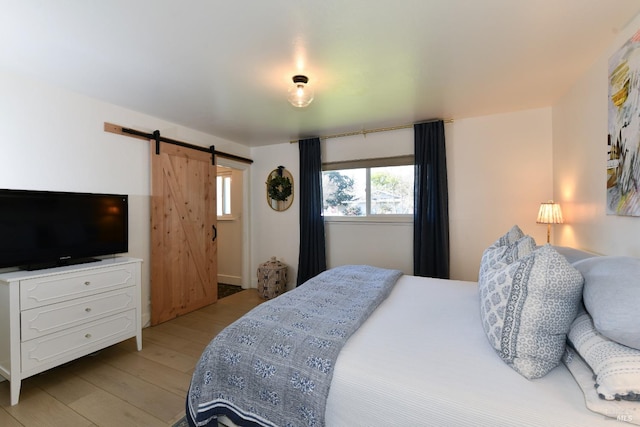 bedroom featuring light wood-style floors and a barn door