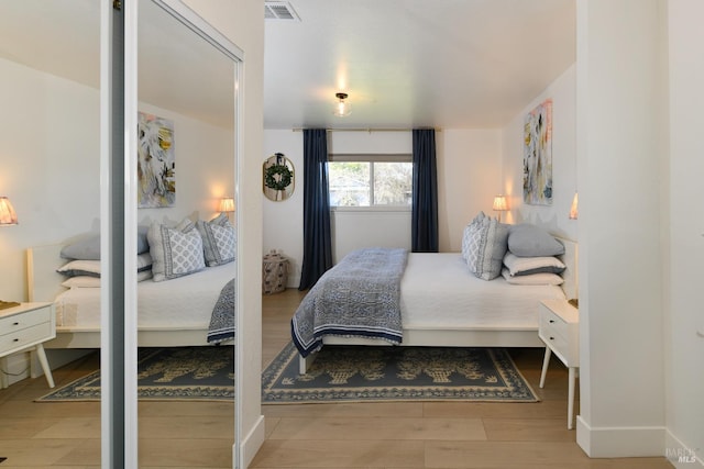 bedroom with visible vents, baseboards, and wood finished floors