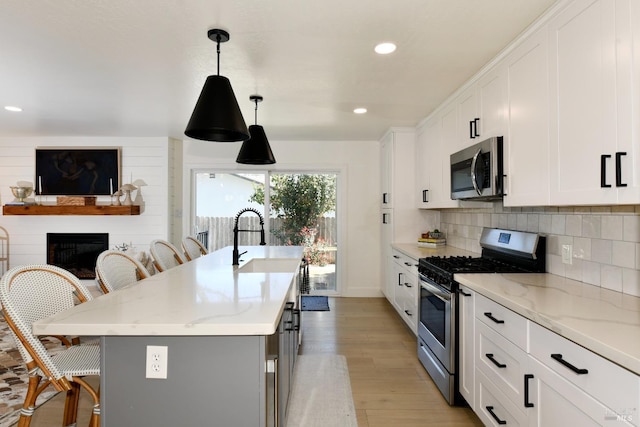 kitchen featuring a glass covered fireplace, appliances with stainless steel finishes, a kitchen bar, and decorative backsplash