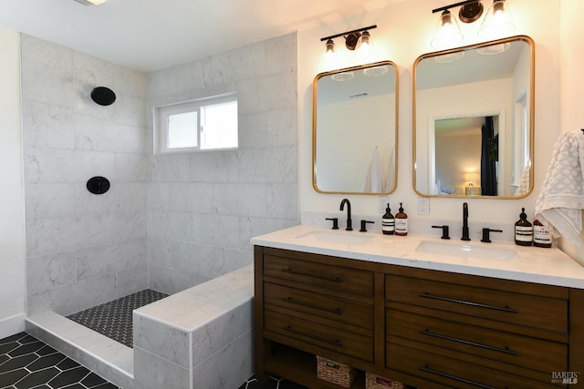 full bath featuring double vanity, tiled shower, and a sink