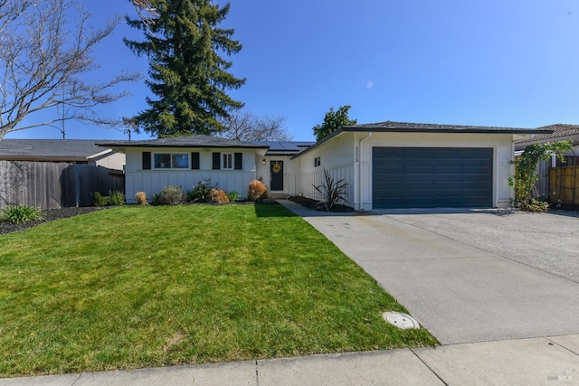 ranch-style home featuring driveway, a front lawn, fence, a garage, and solar panels