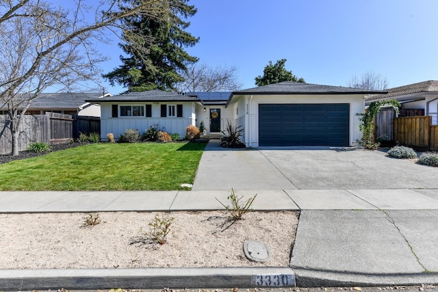 ranch-style home featuring a garage, solar panels, a front lawn, and fence