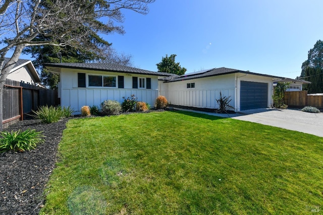 single story home featuring board and batten siding, solar panels, a front lawn, and fence