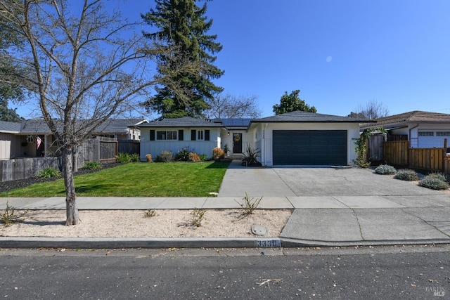 ranch-style home featuring driveway, a front lawn, fence, an attached garage, and solar panels