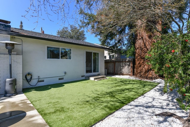 back of property featuring brick siding, fence, entry steps, a lawn, and crawl space