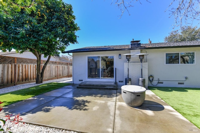 rear view of house featuring stucco siding, a patio, fence, a yard, and crawl space