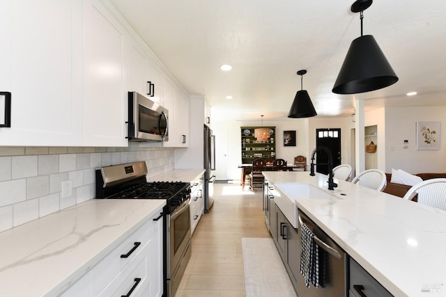 kitchen with pendant lighting, a sink, white cabinetry, appliances with stainless steel finishes, and decorative backsplash