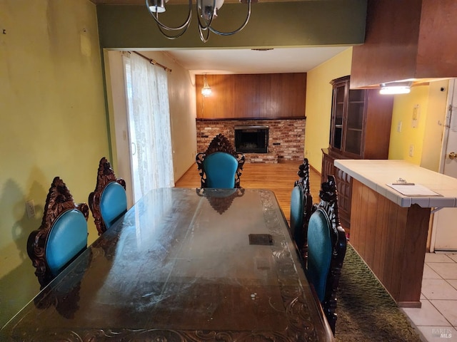 interior space with an inviting chandelier, a brick fireplace, and light tile patterned flooring