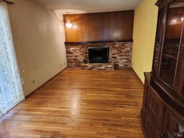 unfurnished living room featuring light wood-style flooring and a brick fireplace